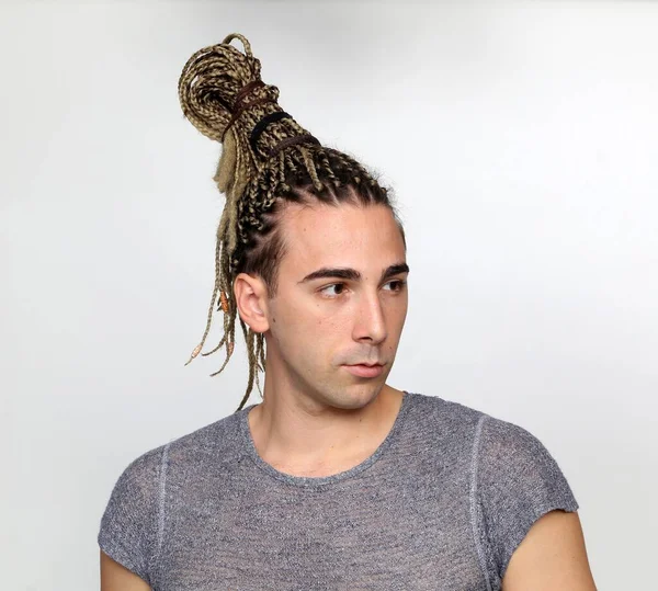 Attractive blonde male model with combination of braids and dreadlocks posing in studio on isolated background. Style, trends, fashion concept.