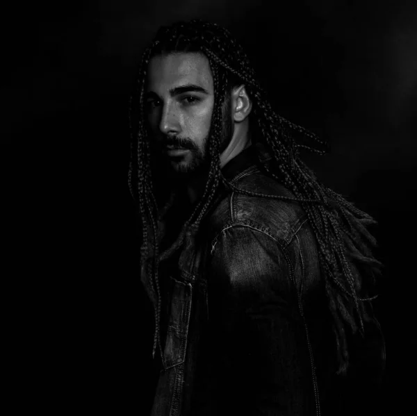 Attractive blonde male model with combination of braids and dreadlocks posing in studio on isolated background. Style, trends, fashion concept.