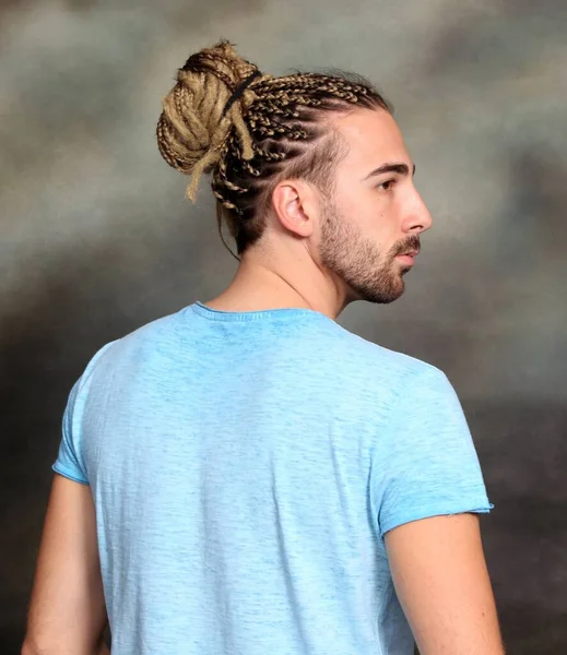 Çekici sarışın erkek model. Örgü ve rastalı saç örgülerinin kombinasyonu. Stüdyoda izole edilmiş arka planda poz veriyor. Tarz, trendler, moda konsepti.