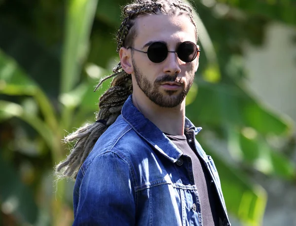 Attractive, young blonde bearded male model with combination of braids and dreadlocks posing in the wild. Style, trends, fashion concept.