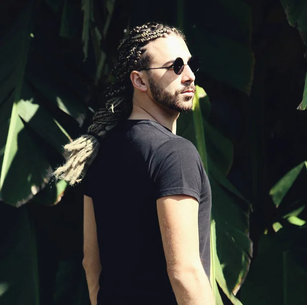 Attractive, young blonde bearded male model with combination of braids and dreadlocks posing in the wild. Style, trends, fashion concept.