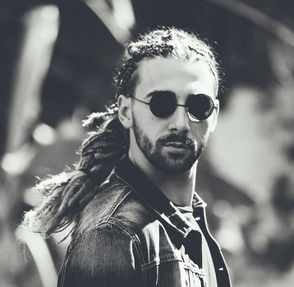 Attractive, young blonde bearded male model with combination of braids and dreadlocks posing in the wild. Style, trends, fashion concept.