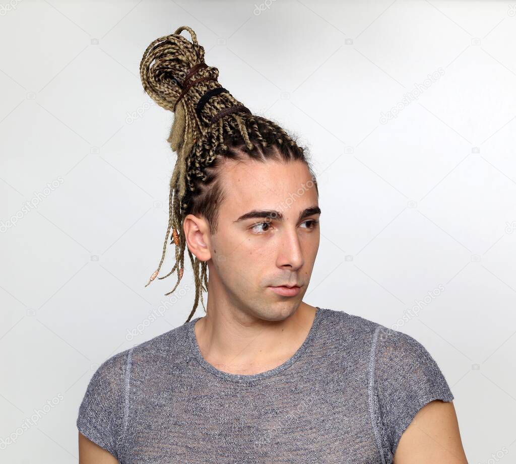 Attractive blonde male model with combination of braids and dreadlocks posing in studio on isolated background. Style, trends, fashion concept.