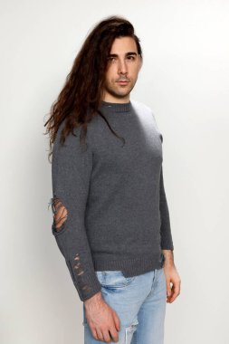 Uzun kıvırcık saçlı çekici genç adam stüdyoda poz veriyor. Tarz, trendler, moda konsepti.