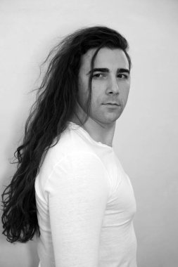 Uzun kıvırcık saçlı çekici genç adam stüdyoda poz veriyor. Tarz, trendler, moda konsepti.