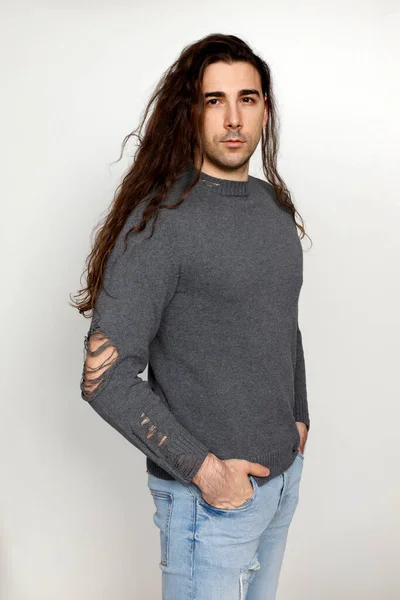非常に長い巻き毛の魅力的な若い男がスタジオでポーズをとっています スタイル トレンド ファッションコンセプト — ストック写真