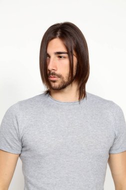 Uzun saçlı ve sakallı çekici erkek model izole bir arka planda stüdyoda poz veriyor. Tarz, trendler, moda konsepti.