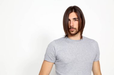 Attractive male model with long hair and beard posing in studio on isolated background. Style, trends, fashion concept. clipart