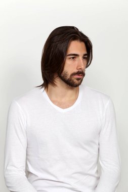 Uzun saçlı ve sakallı çekici erkek model izole bir arka planda stüdyoda poz veriyor. Tarz, trendler, moda konsepti.
