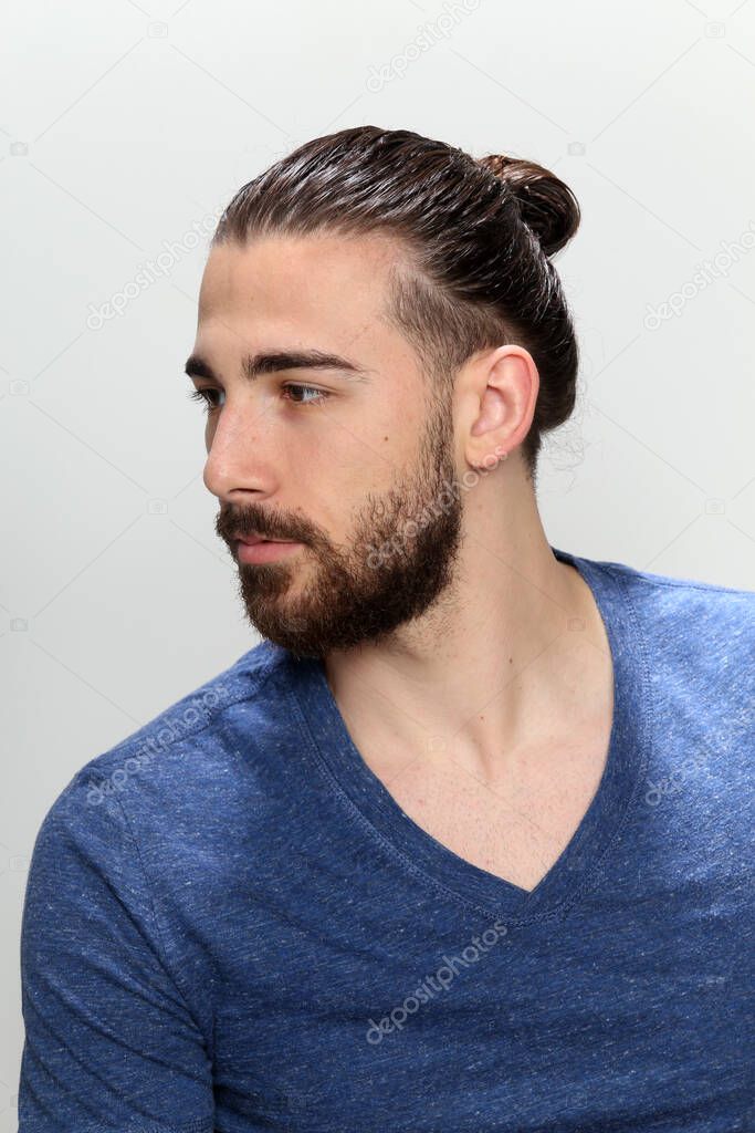 Attractive male model with long hair and beard posing in studio on isolated background. Style, trends, fashion concept.