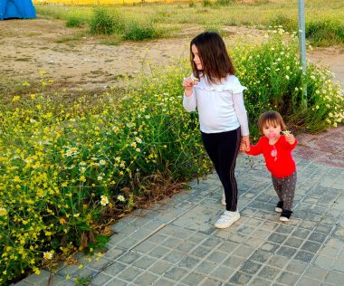 girls picking flowers as they stroll down the street