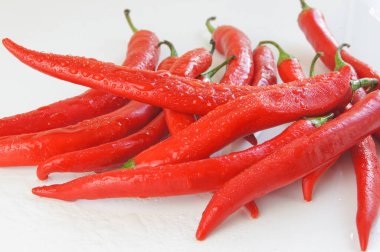 Beyaz zemin üzerinde su damlacıkları olan kırmızı biber.