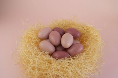 Pembe arka planda saman yuvasındaki paskalya yumurtaları