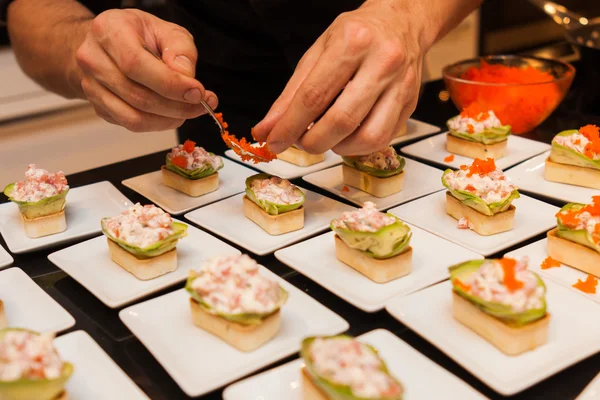 Kırmızı havyar giy cook lezzetli gurme kanepe başlayanlar beyaz plakalar üzerinde hazır.
