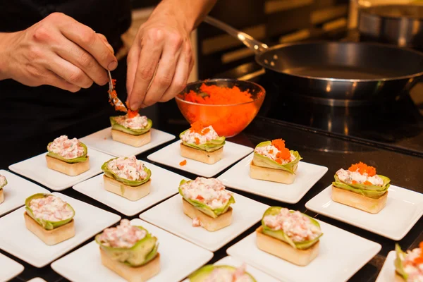 Köchin bereitet köstliche Gourmet-Vorspeisen auf weißen Tellern zu Stockfoto