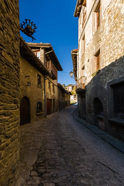 RUPIT, CATALONIA, ESPAÑA, abril de 2016: Una vista de la ciudad medieval de Rupit- calle con brutales casas medievales rústicas — Foto de Stock