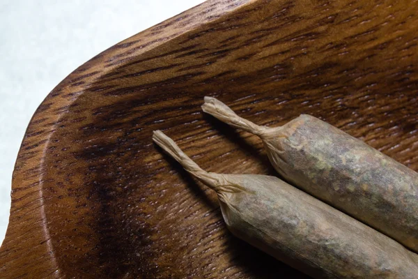 Stock of hand made marijuana joints on wooden platter — Stock Photo, Image