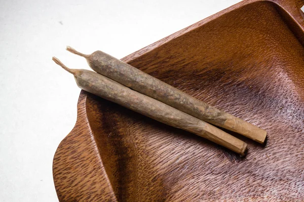 Stock of hand made marijuana joints on wooden platter — Stock Photo, Image