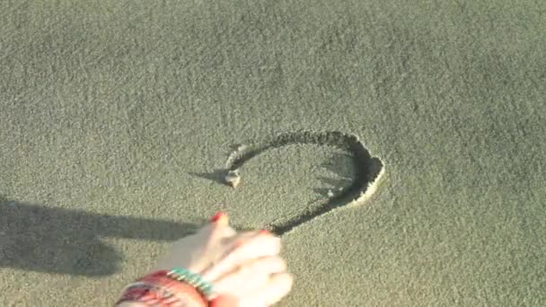 Bir kalp işareti bir kum üzerine çizmek ve dalga tarafından yıkayın
