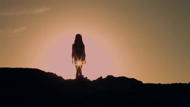 Женский силуэт стоит на подсветке солнца — стоковое видео