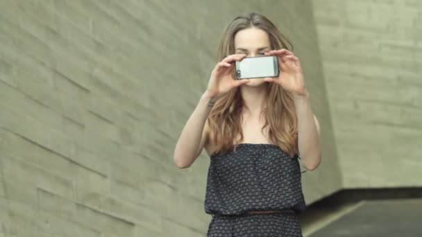 Красивая девушка модель девушка снимает видео фото на мобильный телефон — стоковое видео