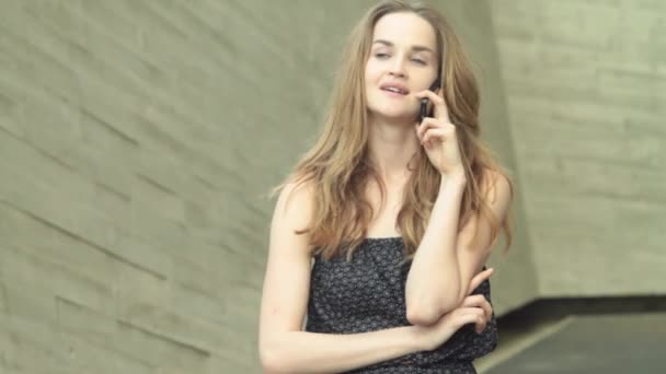 Красивая девушка-модель разговаривает по мобильному телефону и ищет кого-то — стоковое видео