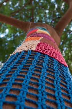 Yarnbombing. Knitted ornaments for trees. Decoration. Hand made pattern. ulti-colored wicker cover for trees.  clipart