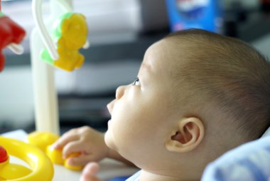 Kız bebek oturmak oyuncak araba ve seyir üzerinde izlemek için bir şey.