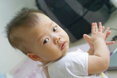 Asya bebek yere otur ve onun el clap