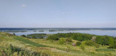 Tepeden güzel nehir manzarası, eski ahşap ev, adalar, yazın öğleden sonra otlar.