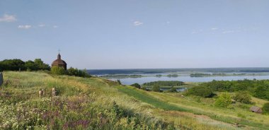 Çayırdan eski ahşap kiliseye, nehre, adalara kadar güzel bir manzara.