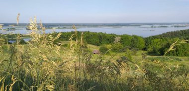 Çayırın, nehrin, adaların güzel manzarası. Yazın, öğleden sonra dağlardan.