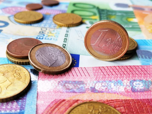 Closeup metal coins on the top of euro banknotes. Cash money.  One hundred, fifty, twenty and ten european bills. Metal coins of one euro and fifty, twenty, ten and five cents on top.