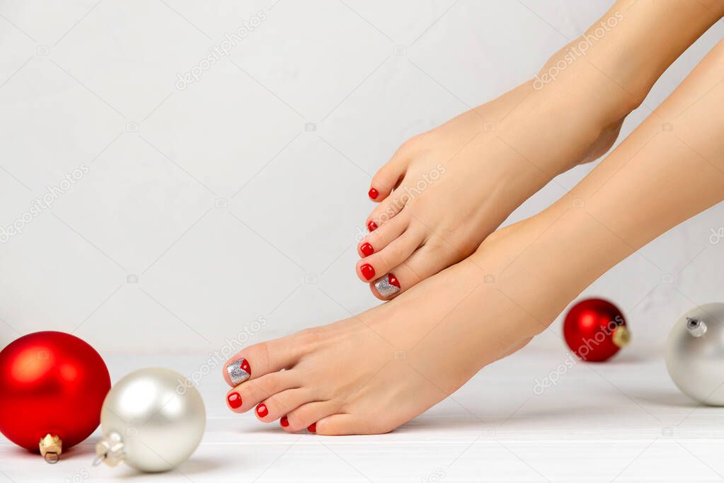 Female legs and christmas ornaments on white background