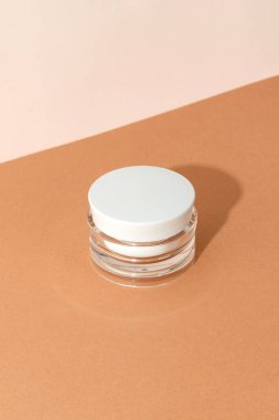 Bej arka planda güneş ışığında bir şişe kozmetik kremi. En düşük biçim kozmetik şablonu