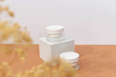 Podyumda güneş ışığında kahverengi arka planda bir şişe kozmetik kremi. En düşük biçim kozmetik şablonu