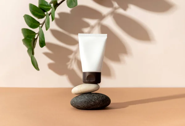 Bej arka planda güneş ışığında dengeleyici taşları olan kozmetik kremler. En düşük biçim kozmetik şablonu