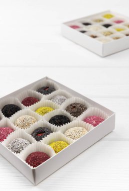 İki kutu vejetaryen şekeri beyaz ahşap masada enerji topları.