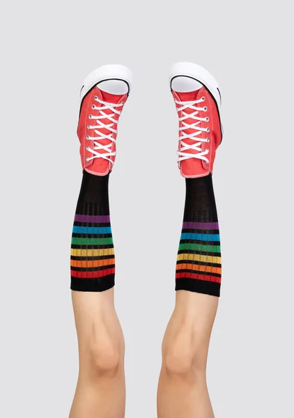 Frauenbeine Stylischen Roten Turnschuhen Und Regenbogensocken Auf Grauem Hintergrund Schuheinkaufskonzept — Stockfoto