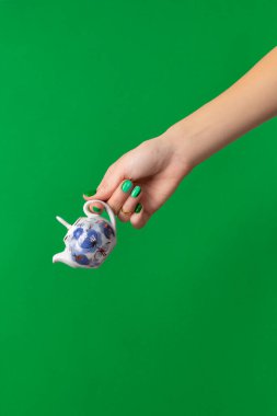 Beautiful groomed womans hand with spring summer nail design on green background