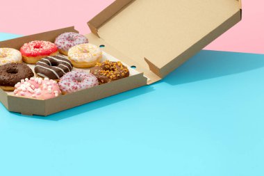 Mavi arka plandaki karton kutuda nefis renkli çörekler.