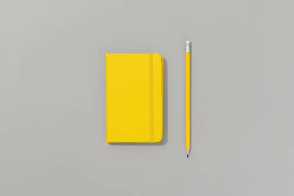 Yellow notepad with pencil on gray background — Stock Photo, Image