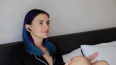 Yatak odasında kablosuz kulaklıklı genç hippi kadınlar müzikten hoşlanırlar.