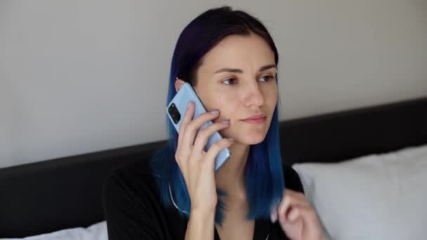 Ženy s modrými vlasy v ložnici mluví na mobilním telefonu — Stock video