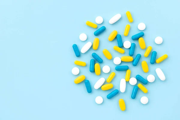 Pilules médicales colorées sur fond bleu. Vue du dessus plat lay — Photo