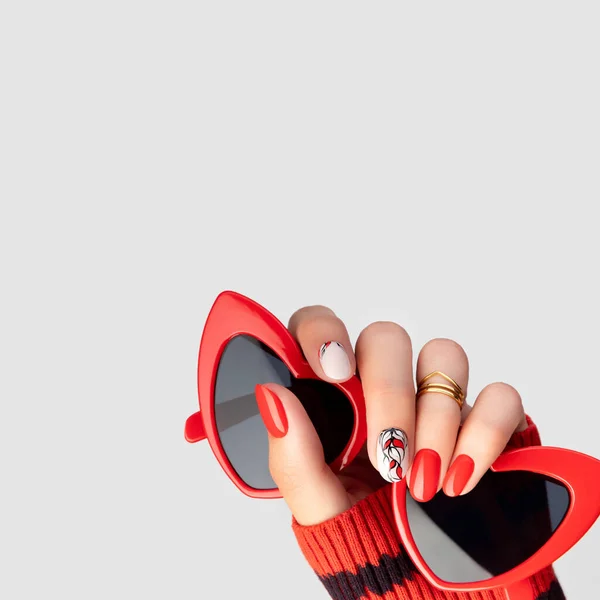 Hermosa mano de las mujeres jóvenes con manicura roja sobre fondo gris — Foto de Stock