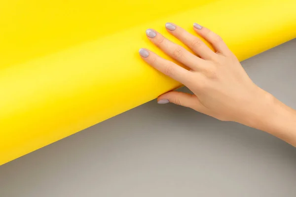 Beautiful womans hand with shiny nail design on gray and yellow background — Stock Photo, Image