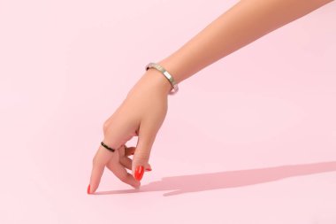 Pembe arka planda kırmızı manikürlü kadın eli. Manikür tasarım eğilimleri