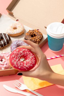 Pembe arka planda karton kutuda nefis renkli çörekler. Çevrimiçi dağıtım.