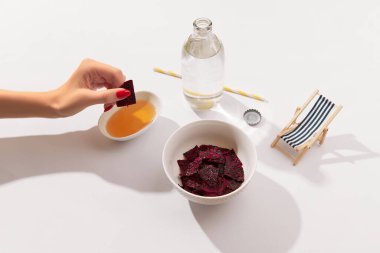 Kurutulmuş ejderha meyveli cips ve sosla beyaz arka planda kadın eli.